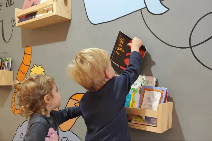 Crianças reunidas em torno de livros no cantinho de leitura